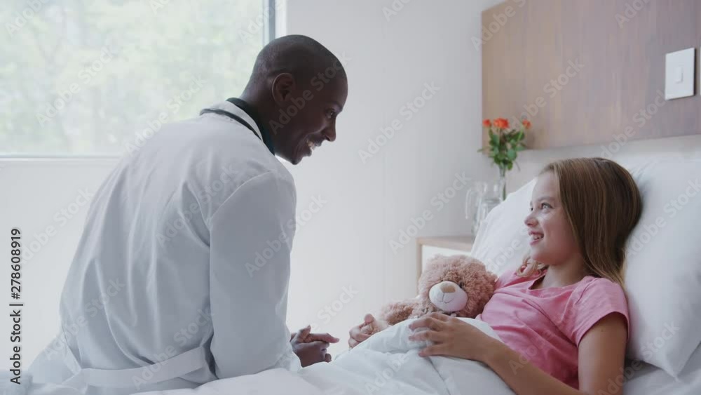 Male Doctor Visiting Girl Lying In Hospital Bed Hugging Teddy Bear Male Doctor Visiting Girl Lying In Hospital Bed Hugging Teddy Bear