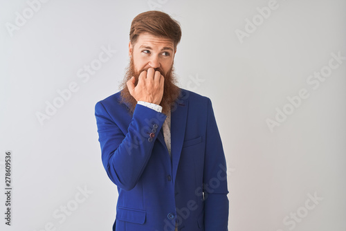 Young redhead irish businessman wearing suit standing over isolated white background looking stressed and nervous with hands on mouth biting nails. Anxiety problem.