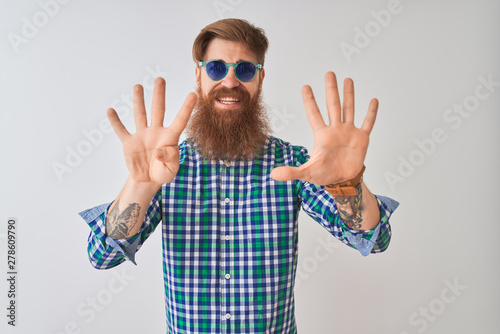 Young redhead irish man wearing casual shirt and sunglasses over isolated white background showing and pointing up with fingers number nine while smiling confident and happy.
