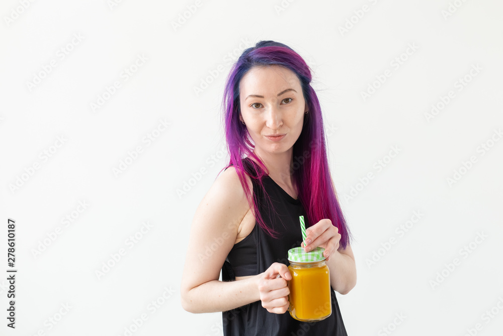 Cute young mixed race hipster girl with colored hair drinks fruit smoothie before starting a yoga class on a white background with copy space. Healthy lifestyle concept. Copyspase. Cute young mixed race hipster girl with colored hair drinks fruit smoothie before starting a yoga class on a white background with copy space. Healthy lifestyle concept. Copyspase.