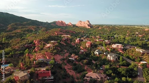 Aerial, drone shot, over buildings towards red sandstone mountains, at the Garden of the Gods, at sunset, on a sunny evening, in Colorado springs, USA photo
