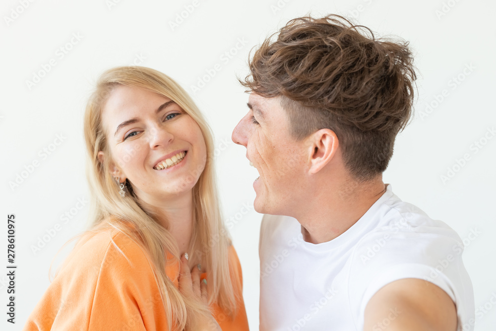 Charming young couple cute blond girl girl take a selfie posing over white background. Concept a young couple of teenagers or millennials In love. Charming young couple cute blond girl girl take a selfie posing over white background. Concept a young couple of teenagers or millennials In love.
