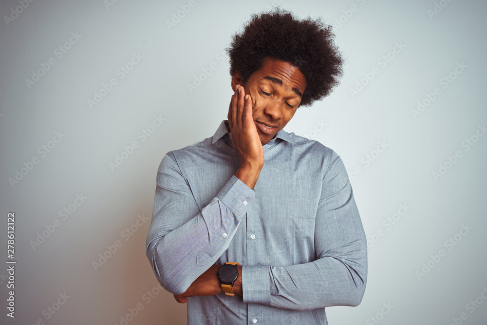 Young african american man with afro hair wearing grey shirt over isolated white background thinking looking tired and bored with depression problems with crossed arms. Young african american man with afro hair wearing grey shirt over isolated white background thinking looking tired and bored with depression problems with crossed arms.