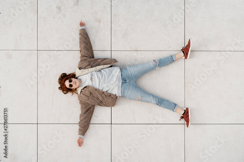 Young beautiful woman lying down on white floor on sunny day photo