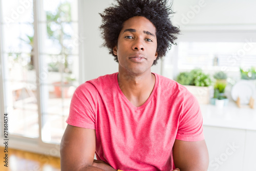 African American business man wearing pink casual t-shirt Relaxed with serious expression on face. Simple and natural with crossed arms