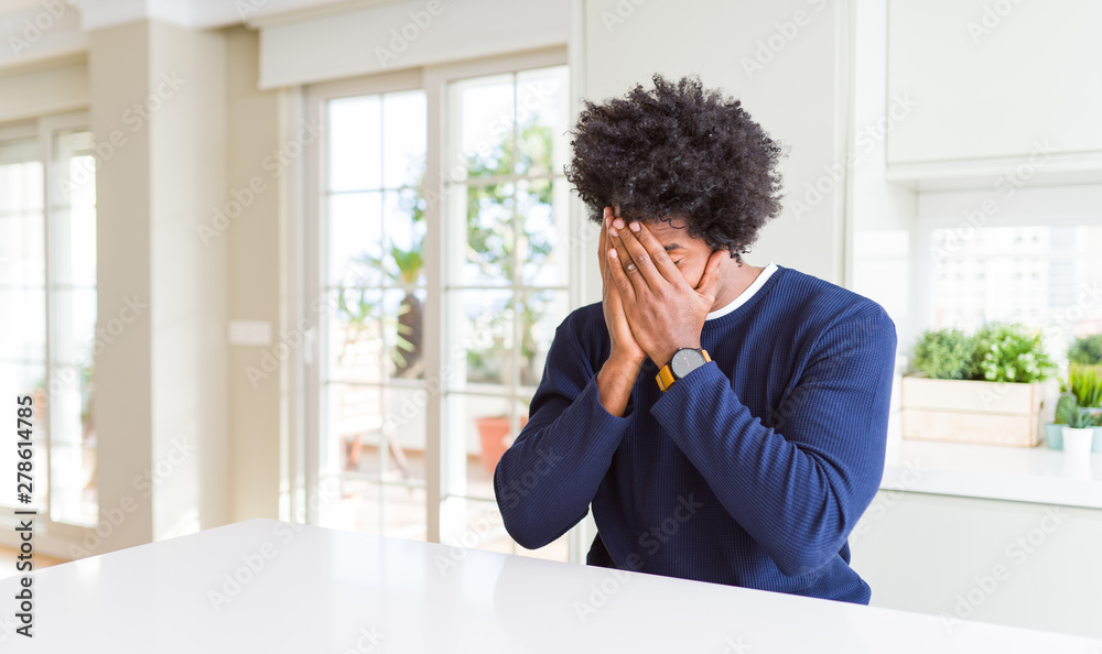 Young african american man wearing casual sweater sitting at home with sad expression covering face with hands while crying. Depression concept. Young african american man wearing casual sweater sitting at home with sad expression covering face with hands while crying. Depression concept.