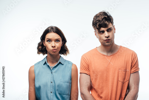 dissatisfied man and woman standing at camera and grimacing on white background
