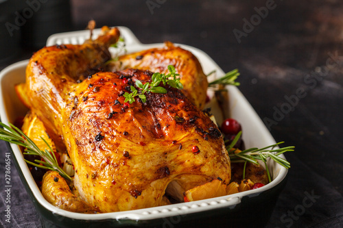 Baked chicken with spices, cranberries, orange and onions in a glass dish.