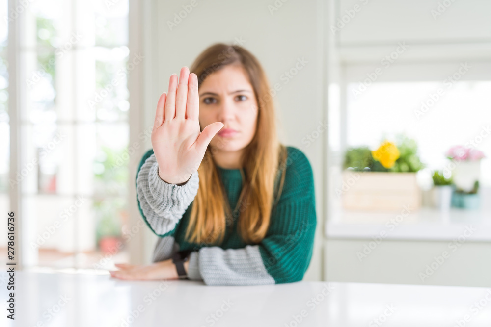 Young beautiful plus size woman wearing casual striped sweater doing stop sing with palm of the hand. Warning expression with negative and serious gesture on the face. Young beautiful plus size woman wearing casual striped sweater doing stop sing with palm of the hand. Warning expression with negative and serious gesture on the face.