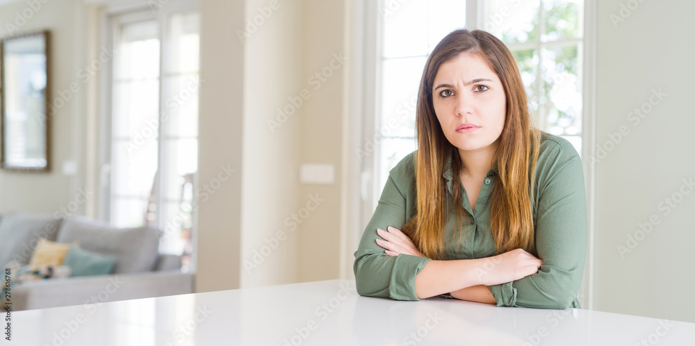 Beautiful young woman at home skeptic and nervous, disapproving expression on face with crossed arms. Negative person.