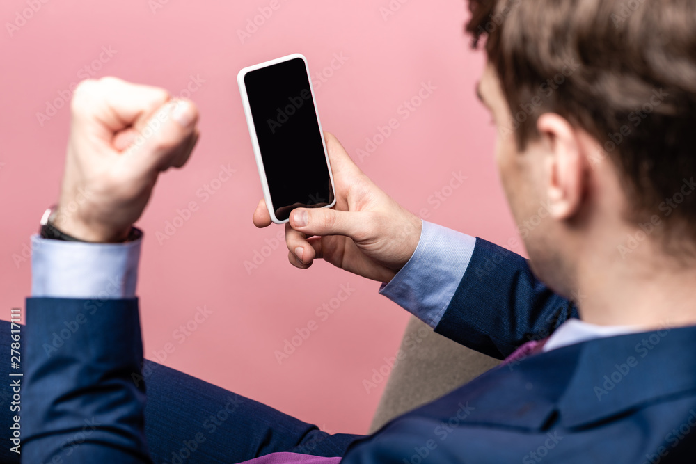 partial view of irritated businessman showing fist while holding smartphone with blank screen isolated on pink partial view of irritated businessman showing fist while holding smartphone with blank screen isolated on pink