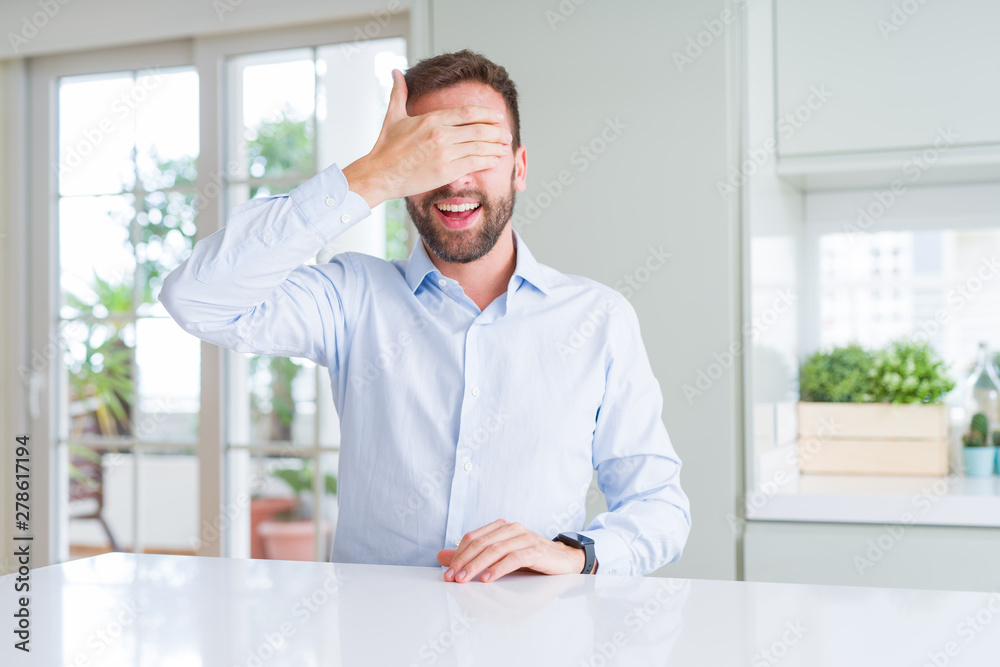 Handsome business man smiling and laughing with hand on face covering eyes for surprise. Blind concept.