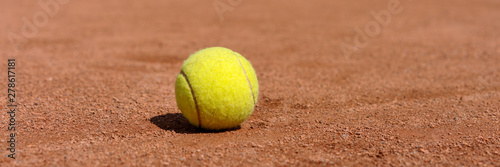 yellow tennis ball on clay court, panoramic photo