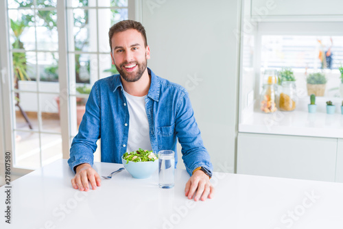 Handsome man eating green peas at home