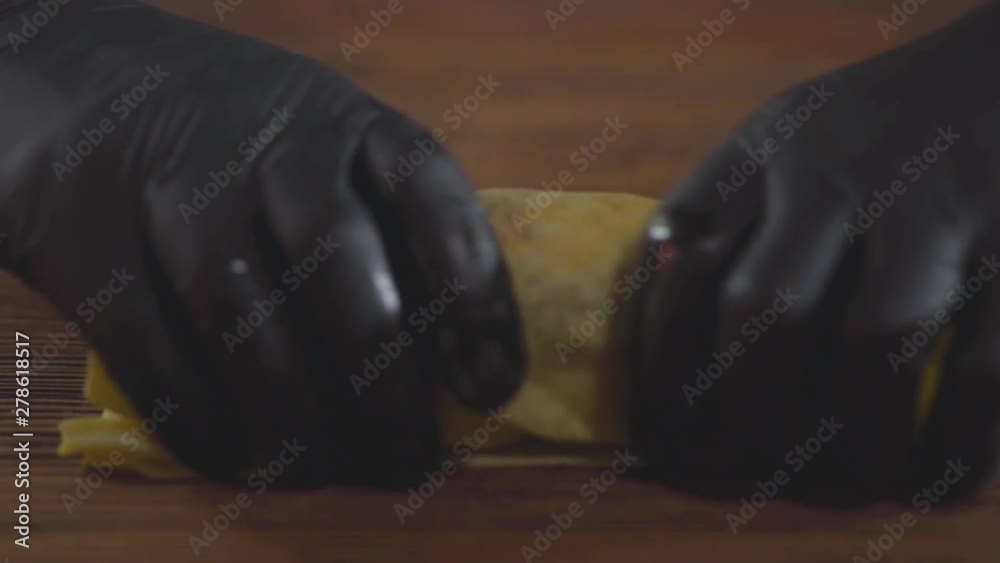 Close-up hands of the skill chef in black rubber gloves making shawarma. The cook rolling shaurma in the pita on the wooden board. Tasty snack preparation. Slow motion. Close-up hands of the skill chef in black rubber gloves making shawarma. The cook rolling shaurma in the pita on the wooden board. Tasty snack preparation. Slow motion.