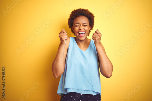 Beautiful african american woman wearing elegant shirt over isolated yellow background excited for success with arms raised and eyes closed celebrating victory smiling. Winner concept.