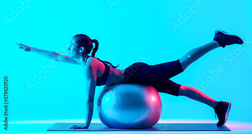 one mixed races woman exercsing fitness pilates exercices isolated on blue blackground photo