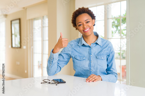 Young beautiful african american woman doing happy thumbs up gesture with hand. Approving expression looking at the camera showing success.
