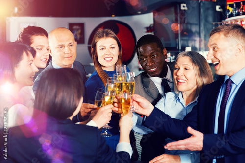 International group of businesspeople toasting with champagne, having fun at office party in nightclub
