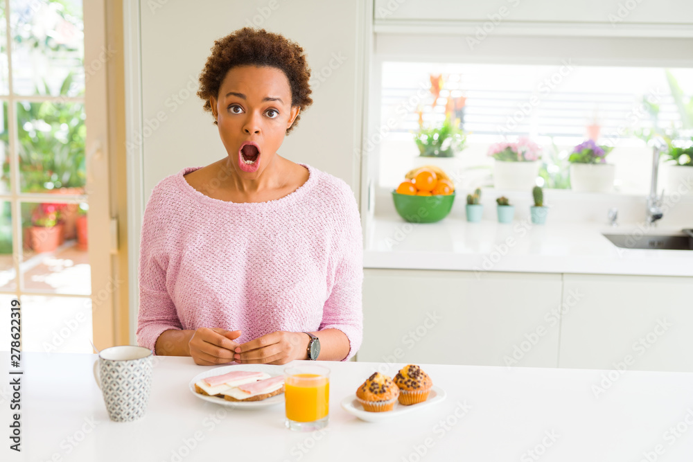 Young african american woman eating breaksfast in the morning at home afraid and shocked with surprise expression, fear and excited face.