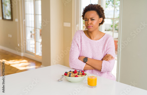 Young african american woman having healthy breakfast in the morning at home skeptic and nervous, disapproving expression on face with crossed arms. Negative person.