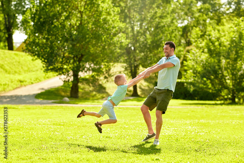 family, leisure and people concept - happy father and little son having fun at summer park