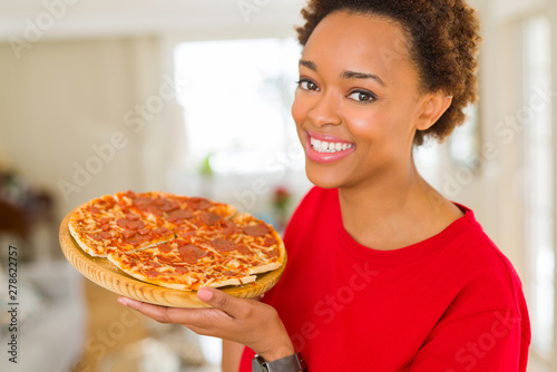 Beautiful young african american woman showing homemade tasty pizza