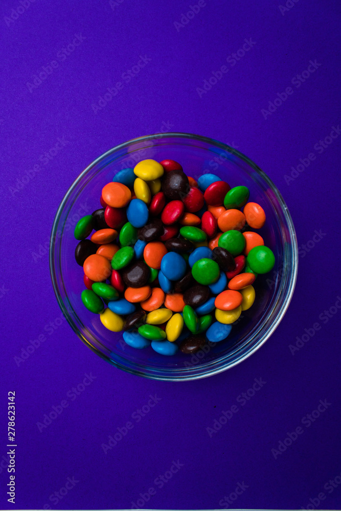 Bowl filled with multicolor candy on a purple background. Bowl filled with multicolor candy on a purple background.