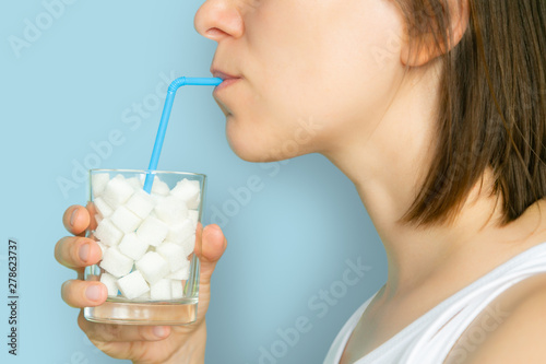 Photographie Excessive sugar consumption concept - female drinking from glass with sugar cube