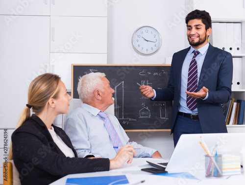 Young man is reading financial report to colleagues on meeting