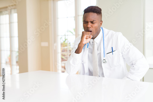 African american doctor man at the clinic feeling unwell and coughing as symptom for cold or bronchitis. Healthcare concept.
