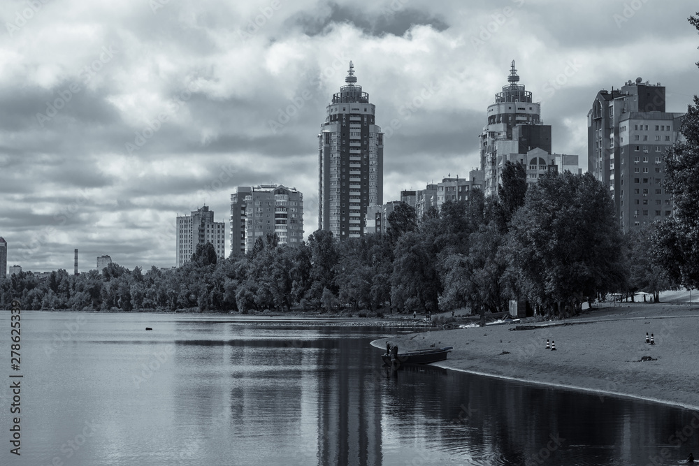 City next to the river on a cloudy day. Tall buildings on the bank of the river