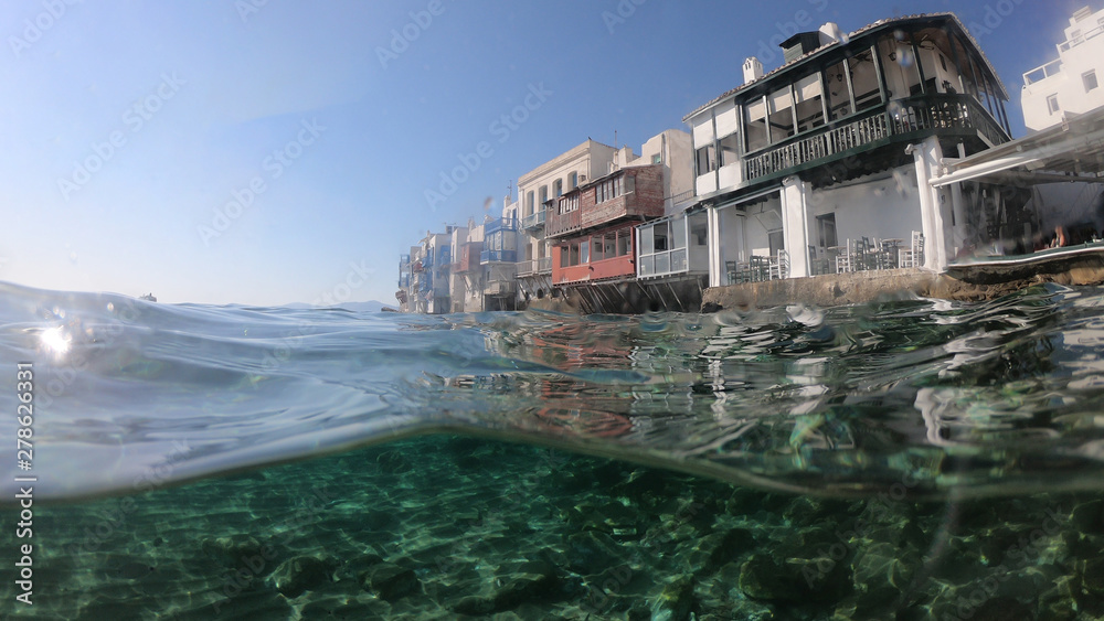 Split of above and underwater photo of iconic and beautiful colourful - whitewashed Little Venice with pure Cycladic architecture, Mykonos island, Greece