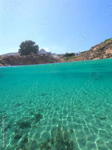 Split of above and underwater photo of iconic and beautiful small cove and sandy clear turquoise beach of Agios Sostis  Mykonos island  Greece