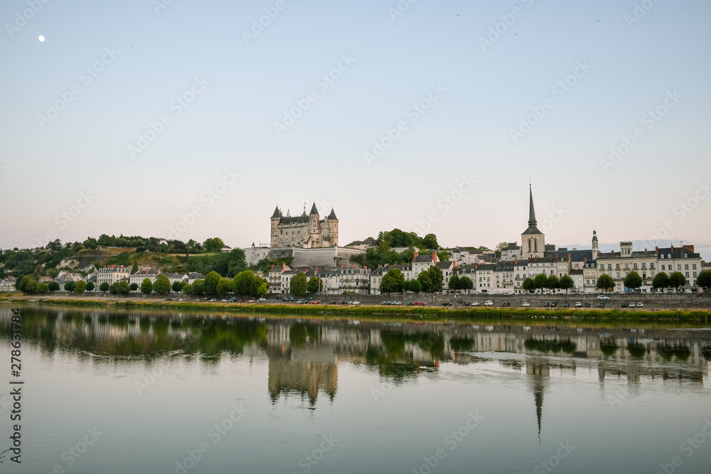 Views of the city of Saumur from the riverbank at dusk, with the castle in the background. Loire Valley, France.