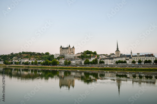 Views of the city of Saumur from the riverbank at dusk, with the castle in the background. Loire Valley, France.