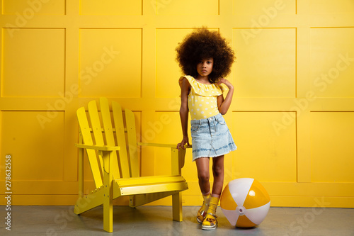 Young girl poses in yellow themed setting