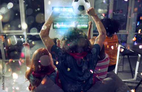 Happy friends of football fans watching soccer on tv and celebrating victory with falling confetti. Double exposure