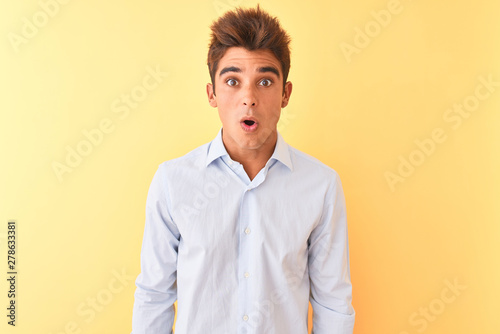 Young handsome businessman wearing elegant shirt over isolated yellow background afraid and shocked with surprise expression, fear and excited face.