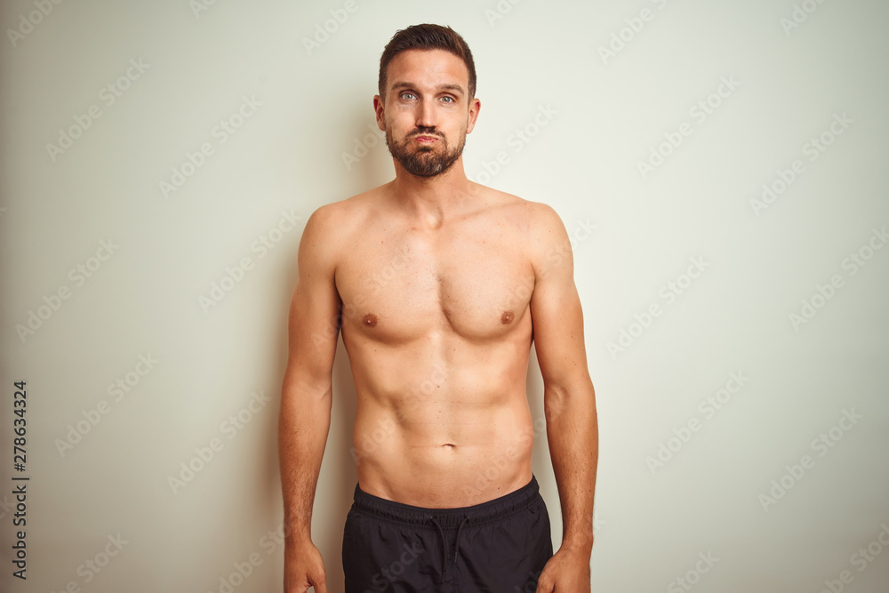 Fototapeta premium Young handsome shirtless man over isolated background puffing cheeks with funny face. Mouth inflated with air, crazy expression.
