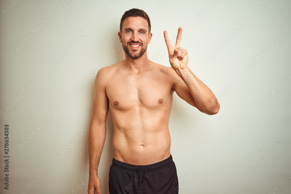 Young handsome shirtless man over isolated background showing and pointing up with fingers number two while smiling confident and happy.