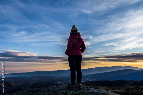 ..Silhouette of Young Woman on the mountain watching the sunset. Moment of reflection. Relaxed woman