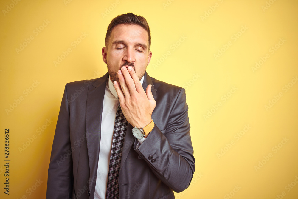 Young handsome business man over yellow isolated background bored yawning tired covering mouth with hand. Restless and sleepiness. Young handsome business man over yellow isolated background bored yawning tired covering mouth with hand. Restless and sleepiness.