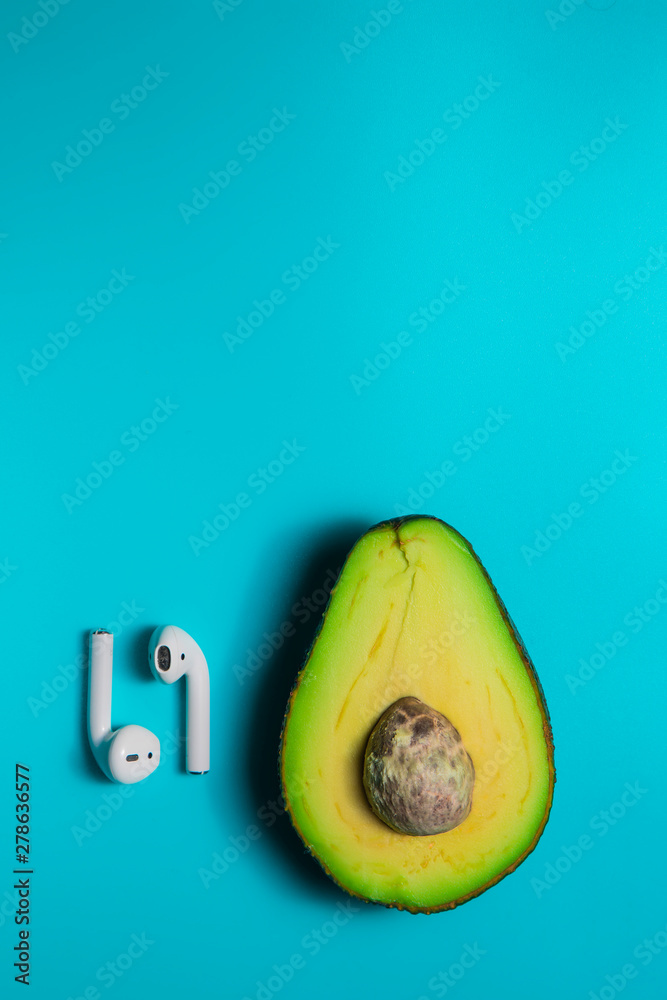 Avocado Isolated on Sky Blue background wis headphones. Music Symbol or Fresh Organic Fruit for Healthy Lifestyle Concept - obrazy, fototapety, plakaty 