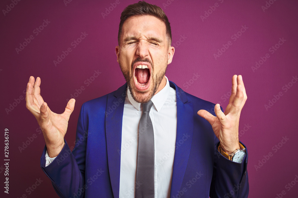 Young handsome business man over purple isolated background celebrating mad and crazy for success with arms raised and closed eyes screaming excited. Winner concept Young handsome business man over purple isolated background celebrating mad and crazy for success with arms raised and closed eyes screaming excited. Winner concept