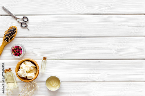 Cosmetics for hair care with jojoba, argan or coconut oilon white wooden background top view mock up photo