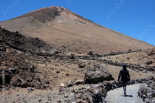 Woman ascending the Teide mountain peak on a dry and rocky volca photo