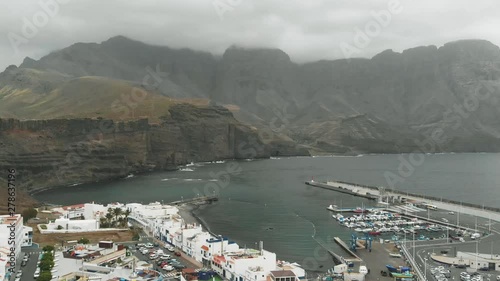 Bay for yachts off the coast of the Atlantic Ocean on an overcast day - aerial view. Massive mountains of high altitude on the background. Agaete, Gran Canaria