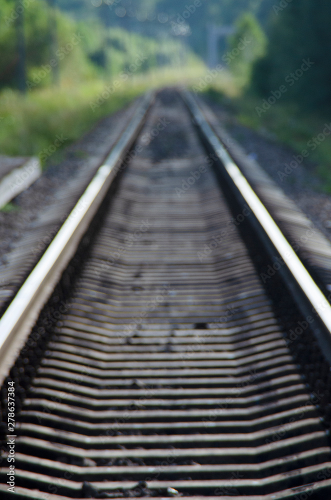 Blurred railway tracks close-up, leading into the distance. Way to nowhere.