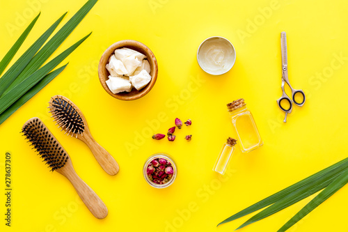 Cosmetics for hair care with jojoba, argan or coconut oil in bottle on yellow background top view